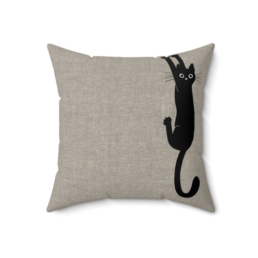 A playful black cat clinging to a pillow with its sharp claws