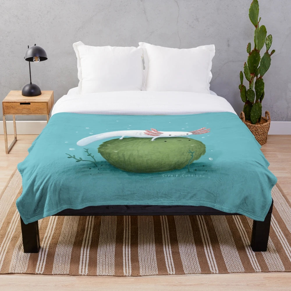 Soft, green plush blanket featuring a cute axolotl sitting on a moss-covered ball