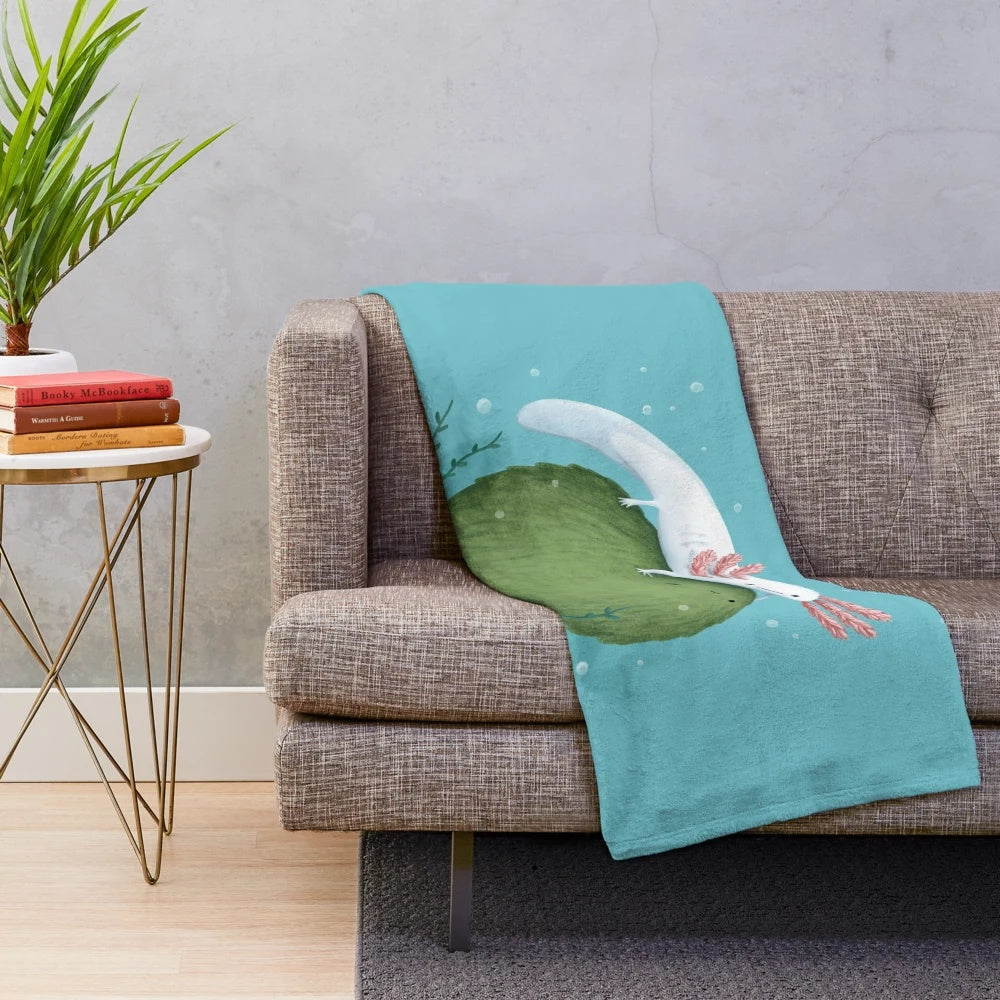 Soft, green plush blanket featuring a cute axolotl sitting on a moss-covered ball