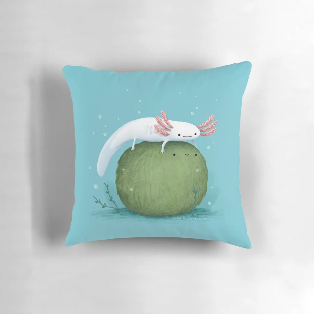 Photograph of a cute, leucistic axolotl sitting on a green, moss-covered ball-shaped pillow
