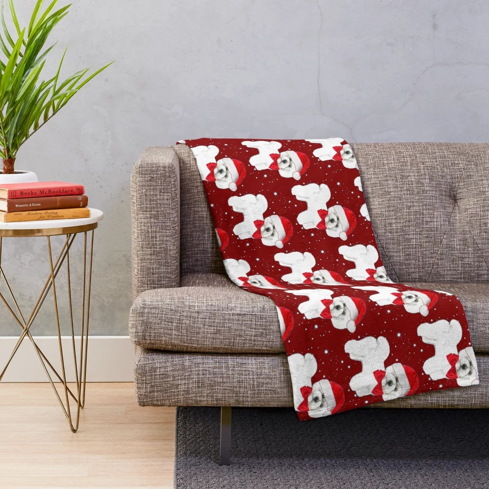Bichon frise dog wearing a Santa hat on a cozy plush blanket
