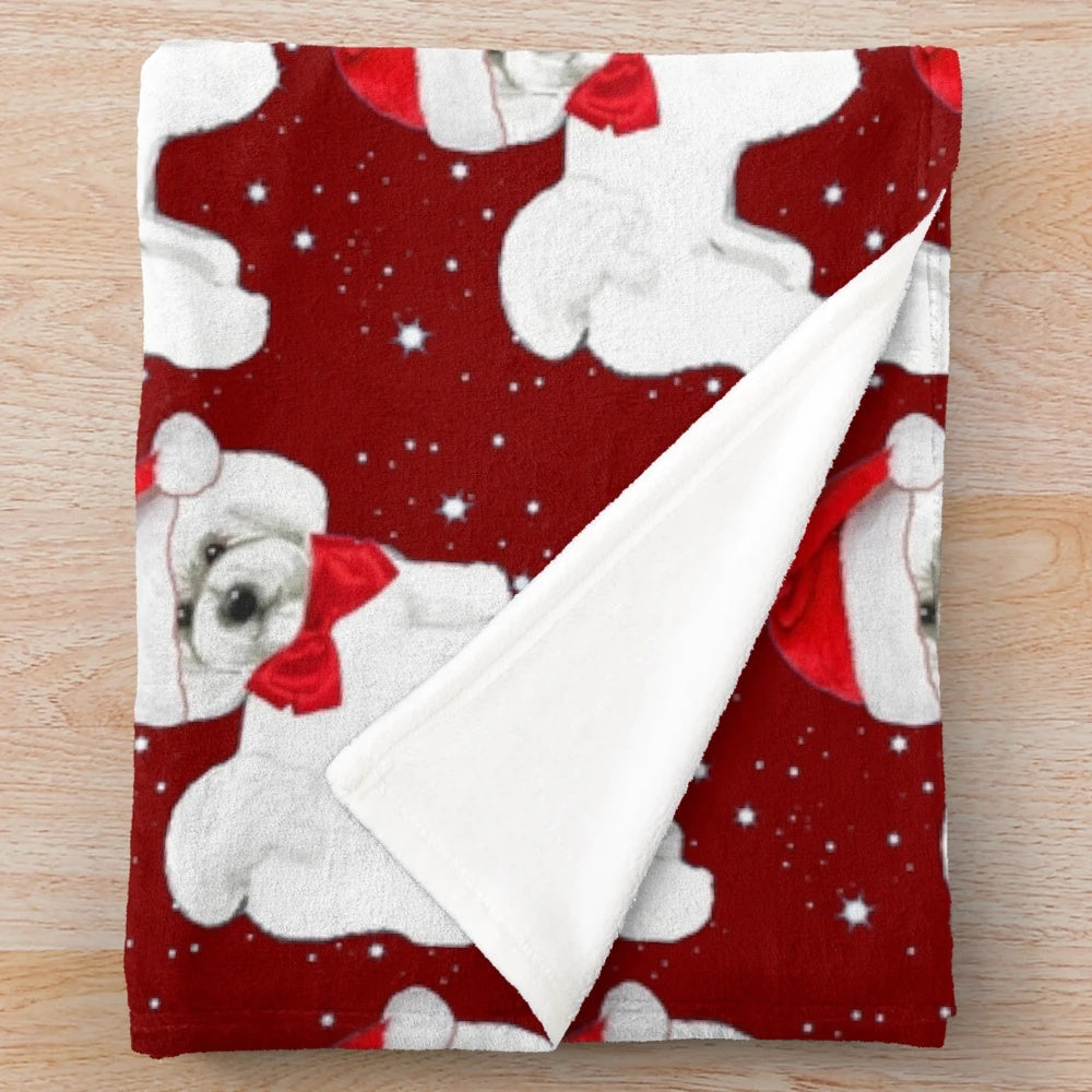 Bichon frise dog wearing a Santa hat on a cozy plush blanket