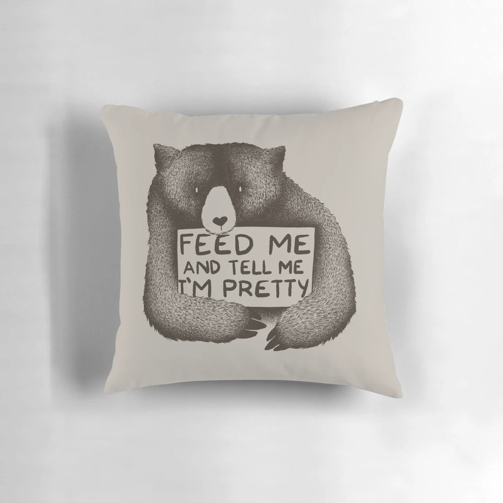 A soft, plush black and white bear pillow with the text "Feed Me and Tell Me I'm Pretty" printed on it.