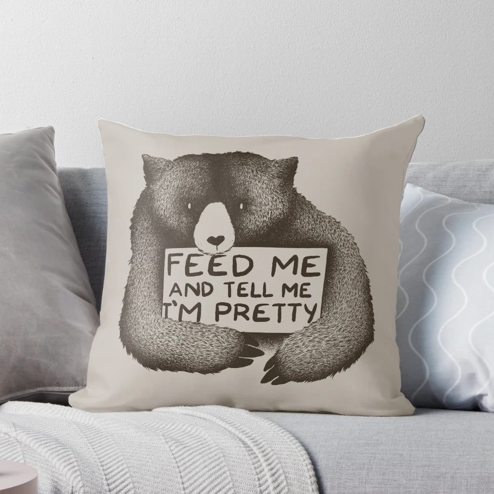 A soft, plush black and white bear pillow with the text "Feed Me and Tell Me I'm Pretty" printed on it.