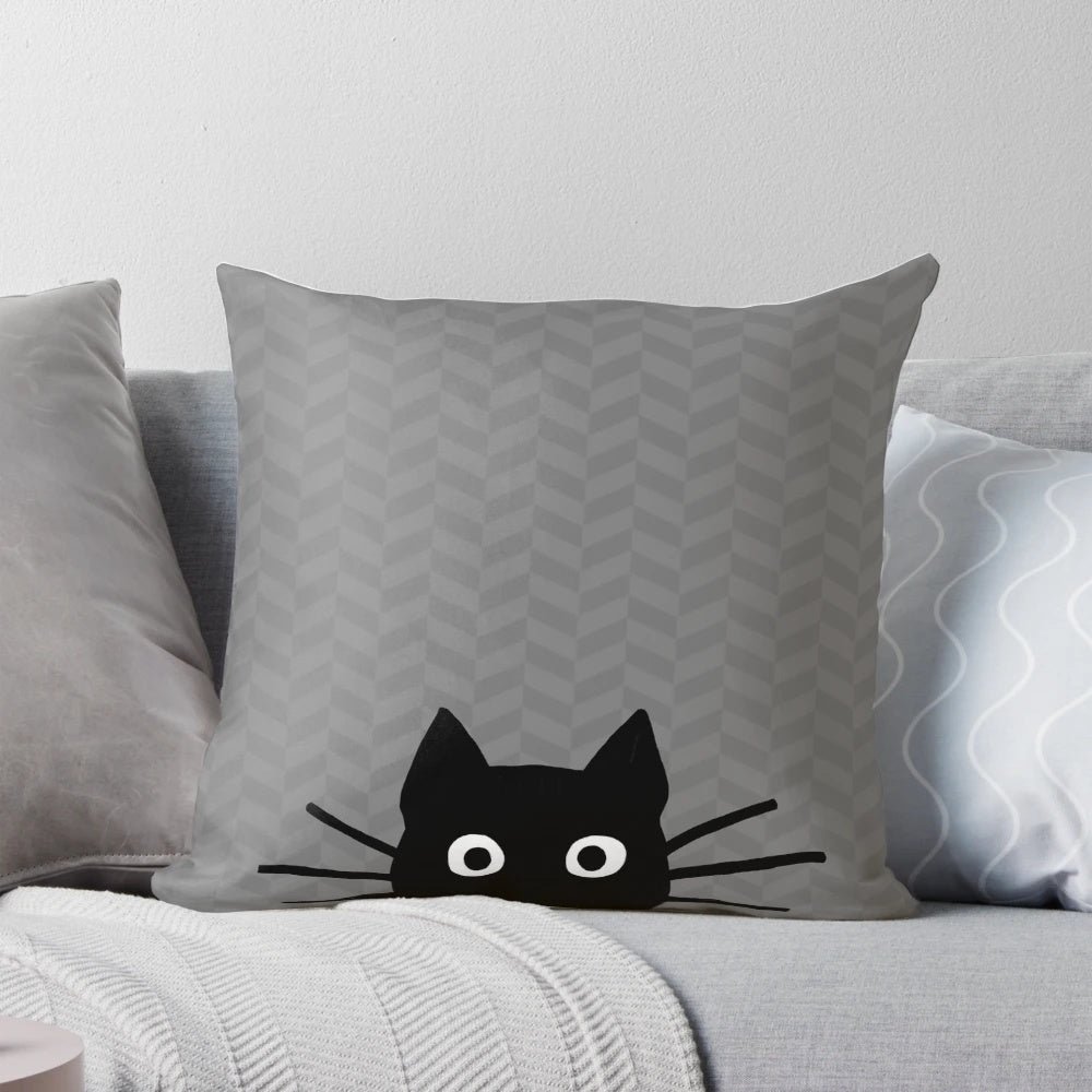 A soft, plush pillow featuring the charming face of a black cat with whiskers.
