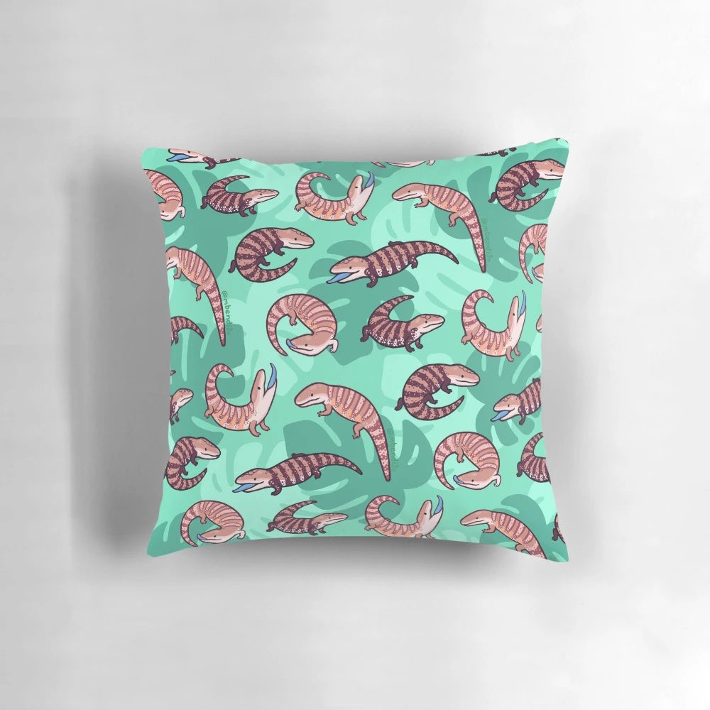 A vibrant and whimsical throw pillow featuring a playful cartoon illustration of a blue tongue skink.