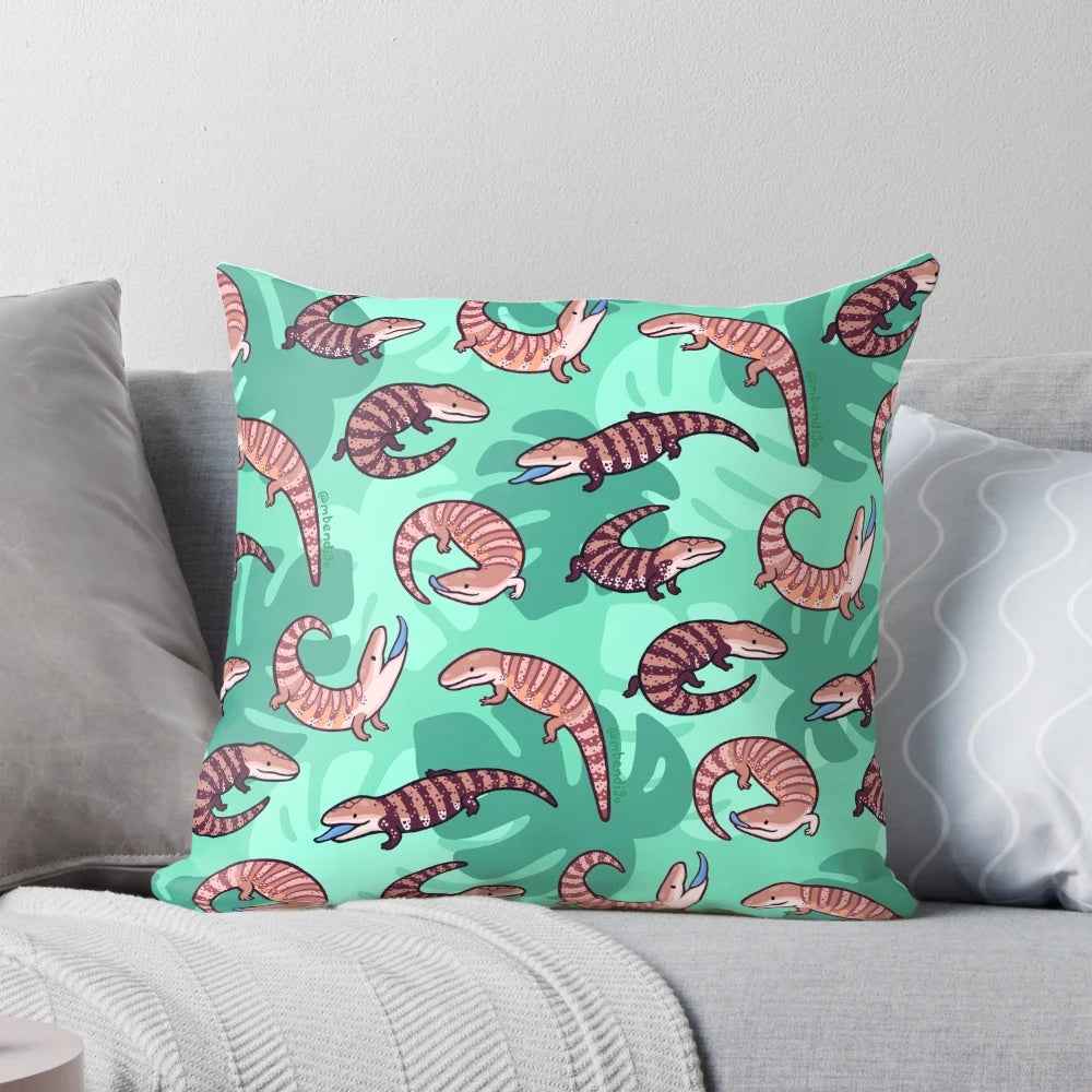 A vibrant and whimsical throw pillow featuring a playful cartoon illustration of a blue tongue skink.