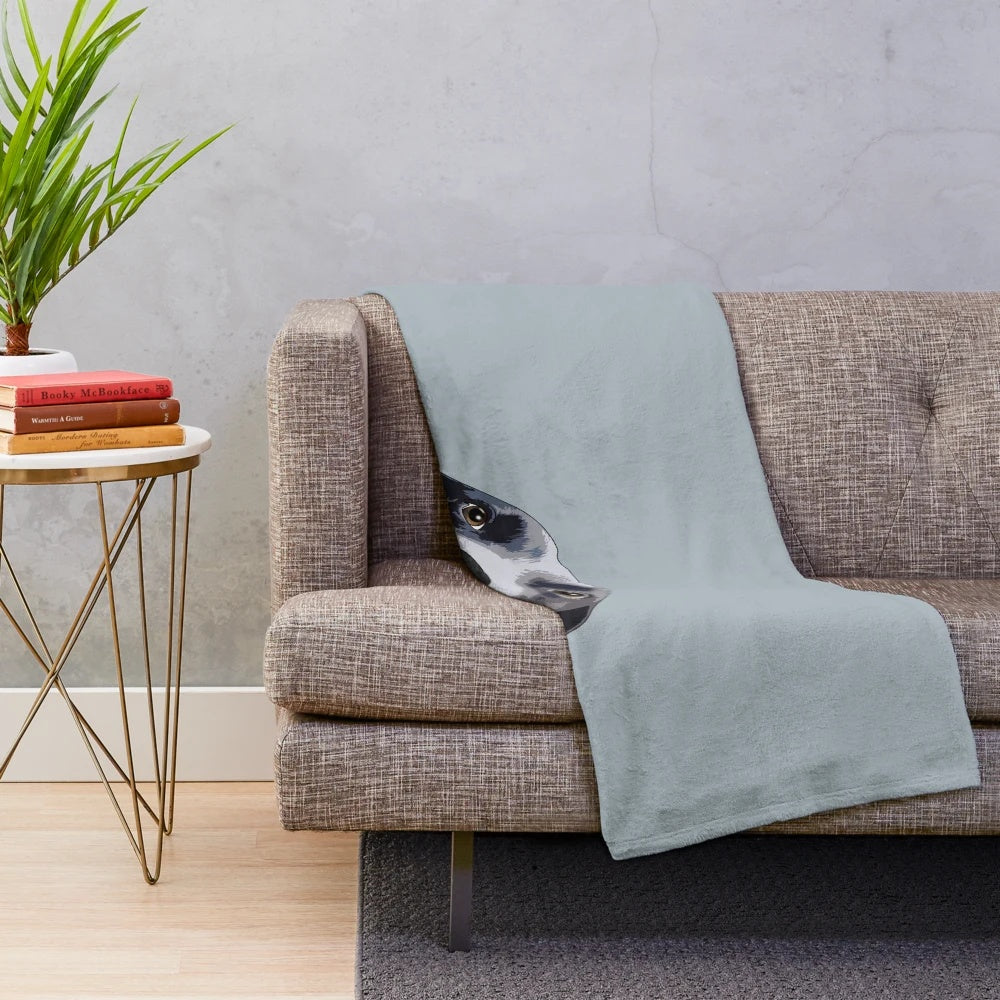 Cute border collie puppy peeking out from a cozy plush blanket