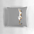 Calico cat humorously clinging to a plush throw pillow