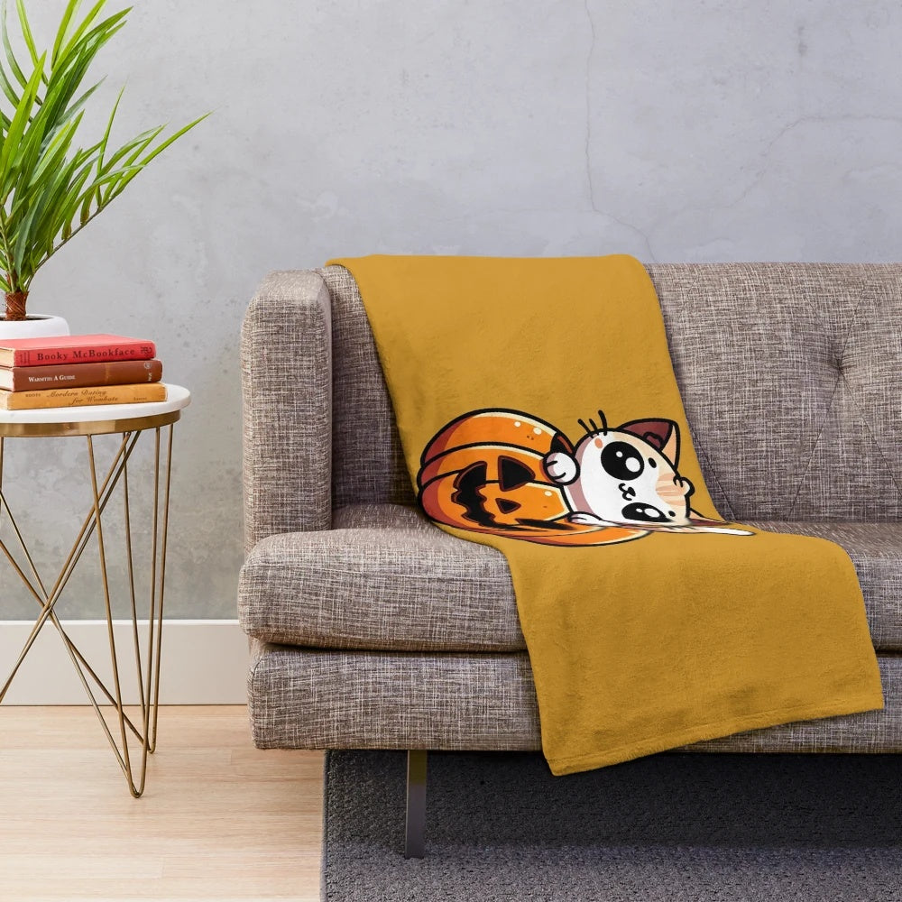 A cozy plush blanket featuring a cute cat peeking out of a pumpkin design