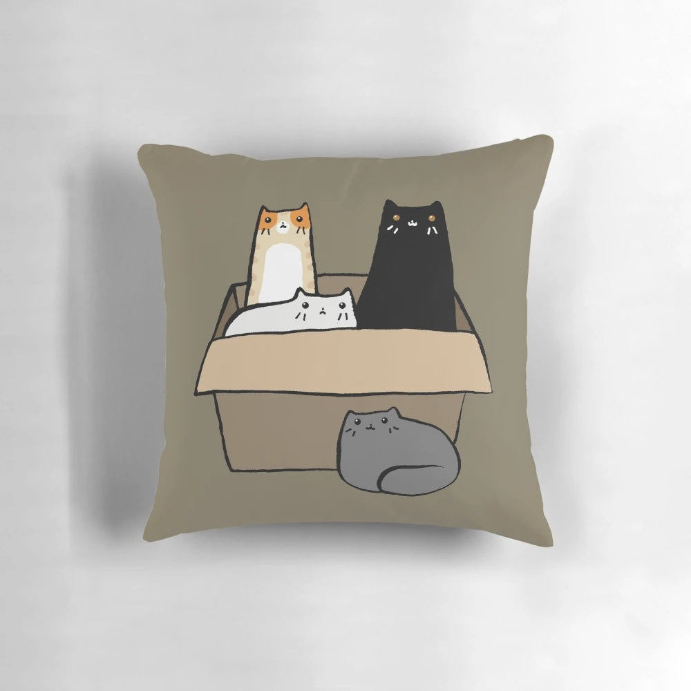 A decorative throw pillow featuring an illustration of various colorful cats in a cardboard box.