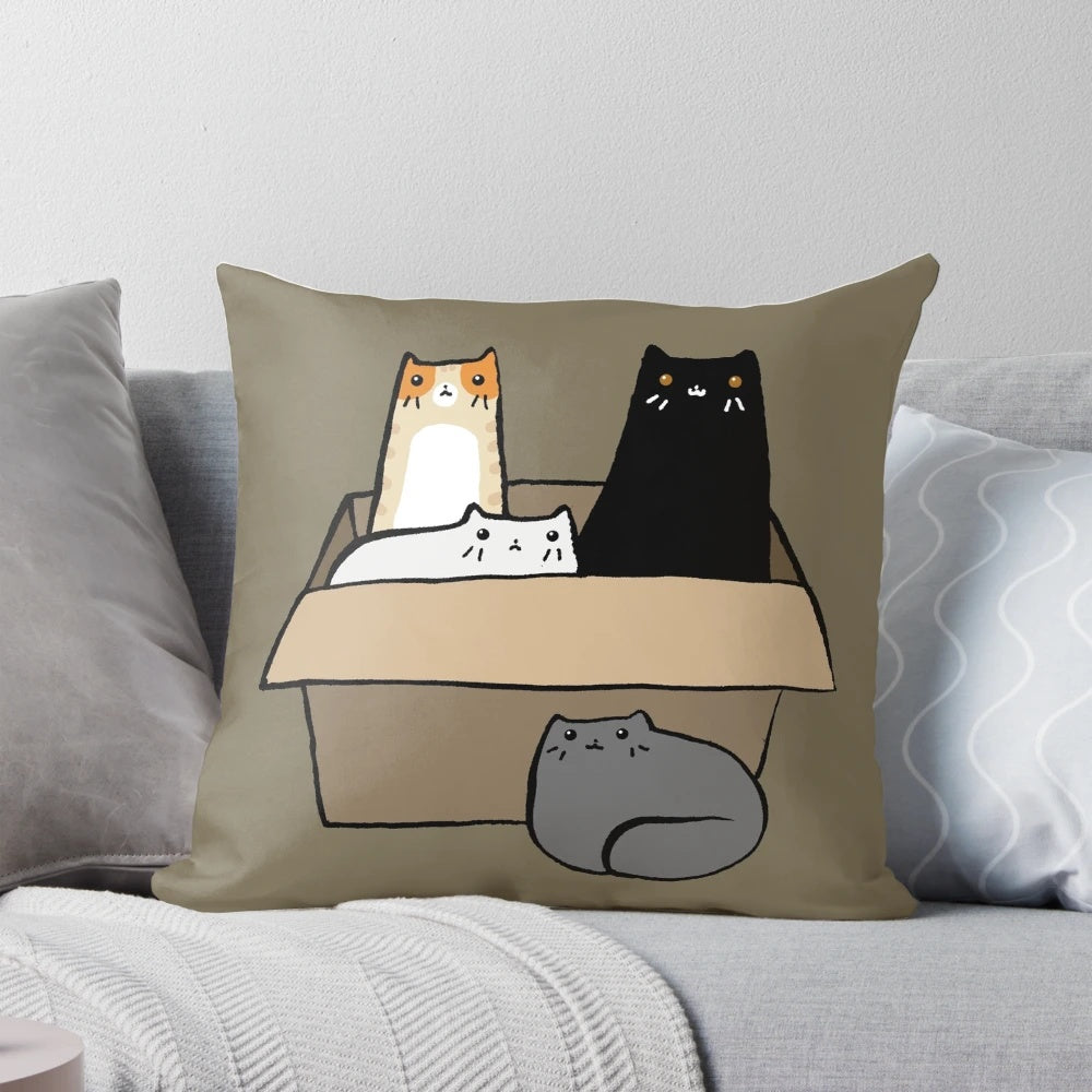 A decorative throw pillow featuring an illustration of various colorful cats in a cardboard box.
