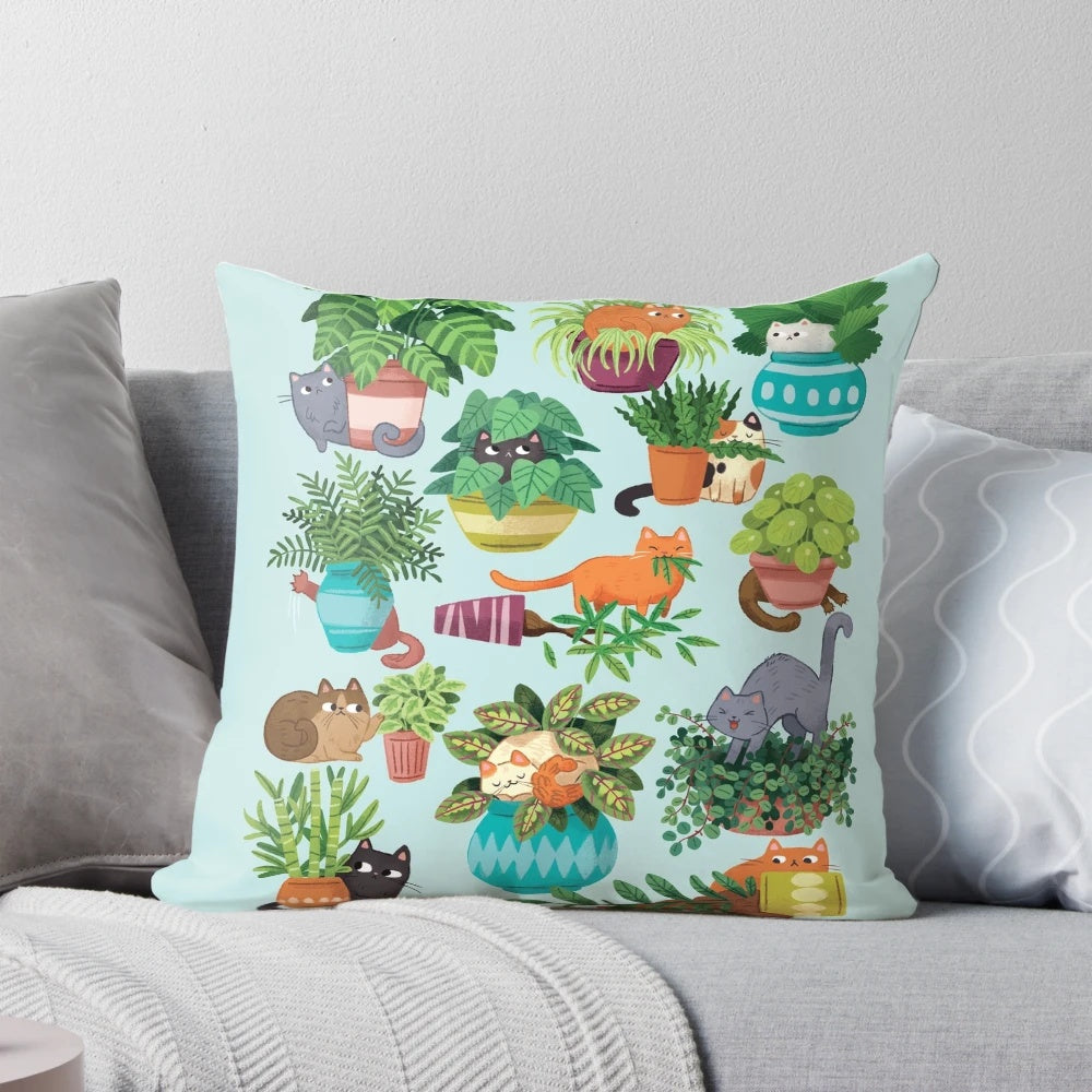 Cute black and tabby cats sitting in a variety of plants on a decorative pillow