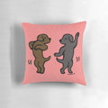 Playful cartoon illustration of a black labrador and a chocolate labrador dancing together on a decorative pillow