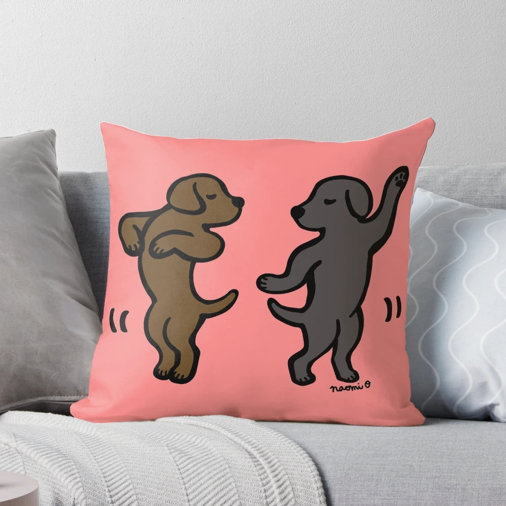 Playful cartoon illustration of a black labrador and a chocolate labrador dancing together on a decorative pillow