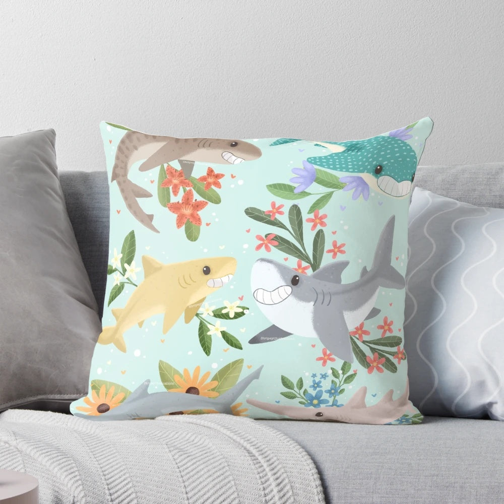 A vibrant, floral-patterned pillow featuring cute, cartoon-style sharks in shades of blue.