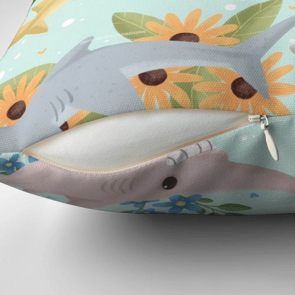 A vibrant, floral-patterned pillow featuring cute, cartoon-style sharks in shades of blue.