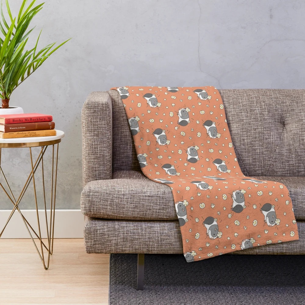 Cute gray and white guinea pig popcorning on a plush blanket with a kawaii pattern design