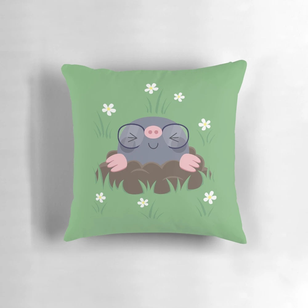 A decorative pillow featuring a pattern of cute, cartoon-style moles wearing eyeglasses and surrounded by grass and white flowers.
