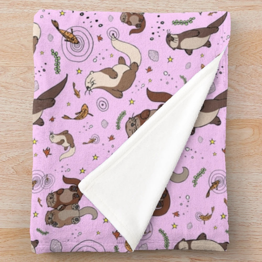 Cozy pink plush blanket featuring a cute otter design