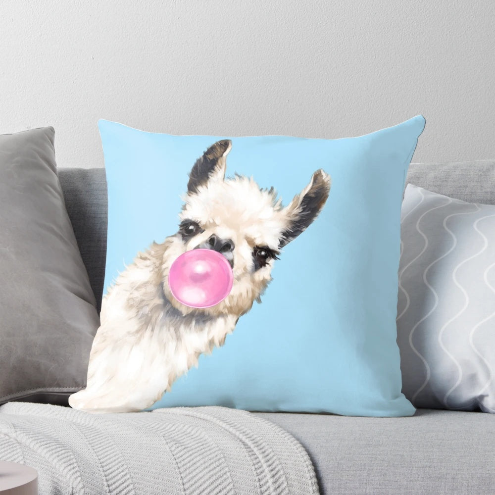 A cute and whimsical pillow featuring a sneaky llama blowing bubble gum in shades of blue and pink.