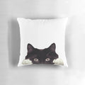 Cute black and white tuxedo cat peeking out from a cozy pillow