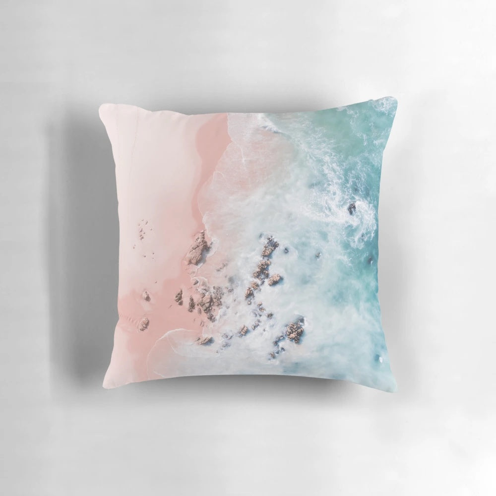 Aerial photograph of a pink sandy beach with crashing waves and a serene ocean view