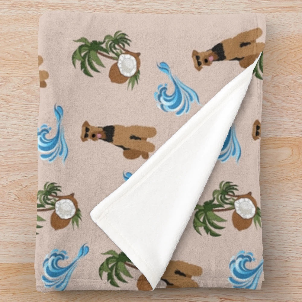 Airedale Terrier dog wearing sunglasses on a plush blanket with a summer pattern of sea waves and coconut palm trees