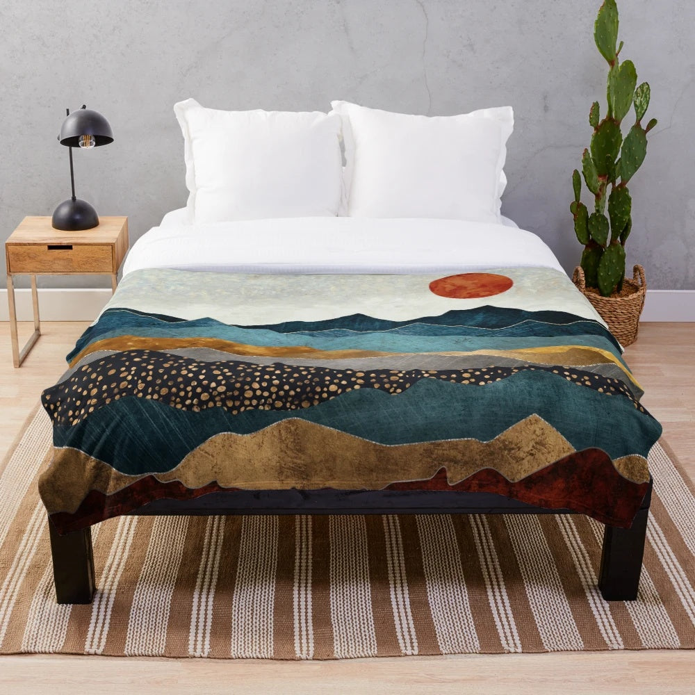 Soft and cozy amber plush blanket with a landscape design depicting a dusk sky over hills and mountains
