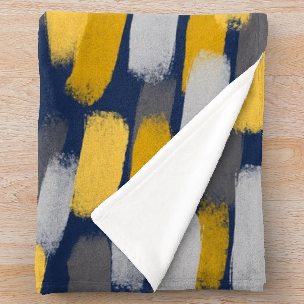 Abstract grey and mustard yellow paint brush effect on a navy blue plush blanket