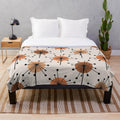 Atomic era inspired plush blanket with vibrant orange and tan sputnik starburst floral pattern