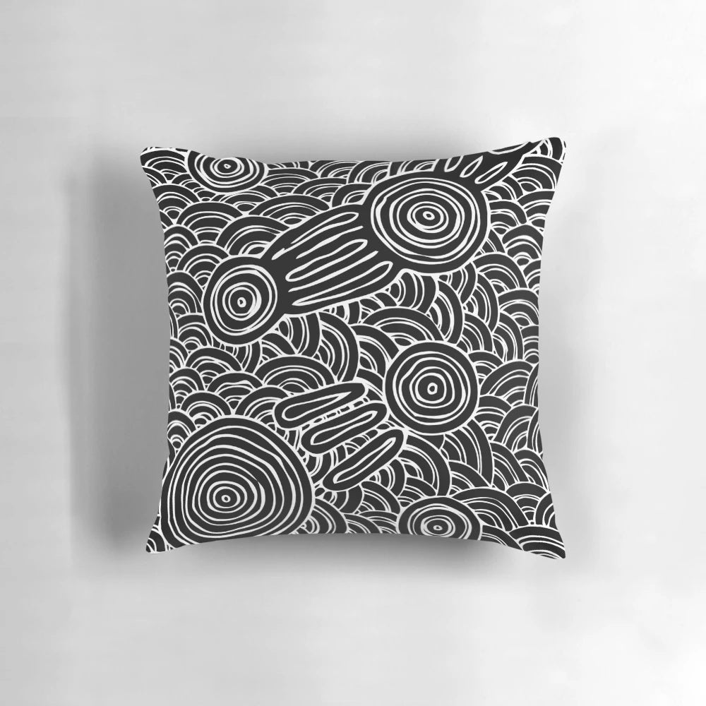 Patterned black and white pillow featuring aboriginal-inspired dot art and symbols