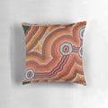 Vibrant acrylic painting of an Australian aboriginal waterhole scene on a decorative throw pillow