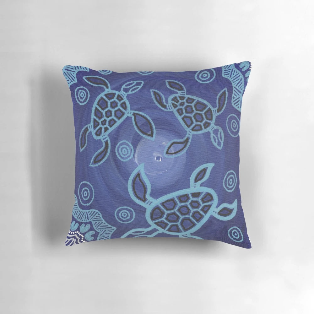 Decorative throw pillow featuring an authentic aboriginal art design of sea turtles in blue, black, and ochre colors.