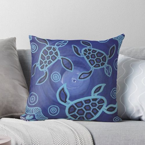 Decorative throw pillow featuring an authentic aboriginal art design of sea turtles in blue, black, and ochre colors.