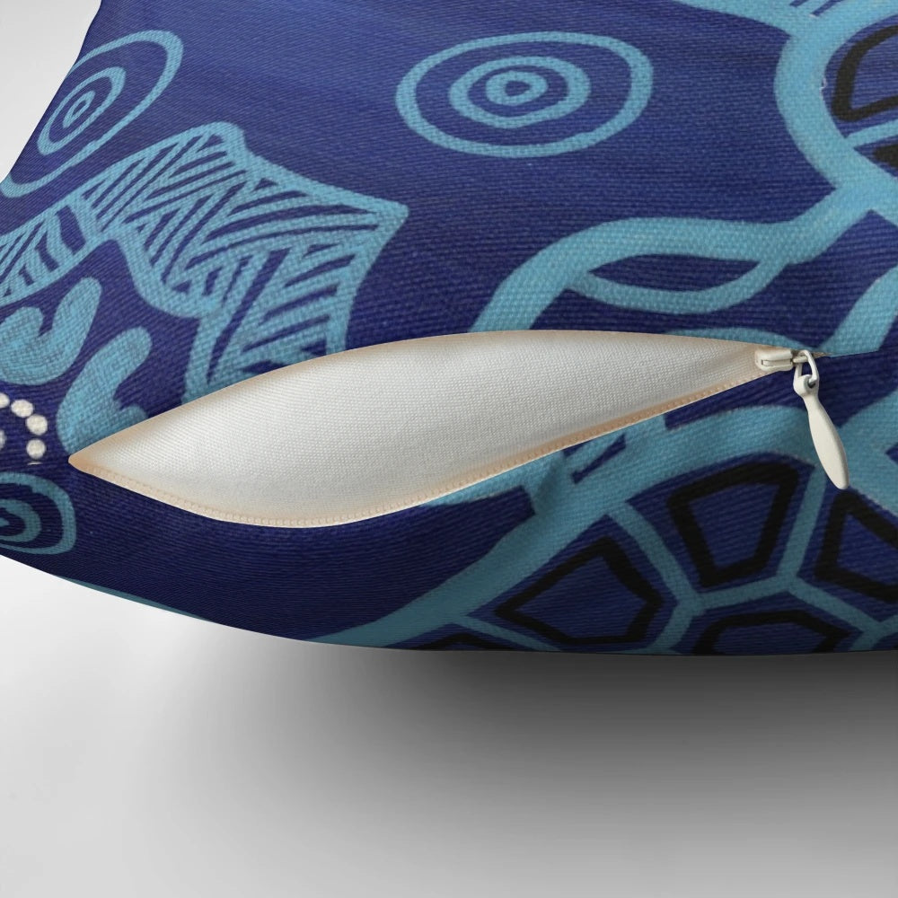Decorative throw pillow featuring an authentic aboriginal art design of sea turtles in blue, black, and ochre colors.
