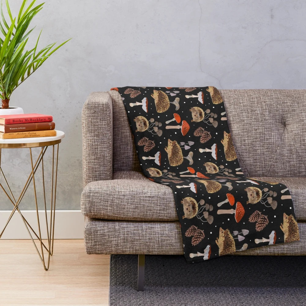 A colorful plush blanket featuring a whimsical design of hedgehogs and mushrooms in an autumn-inspired botanical pattern.