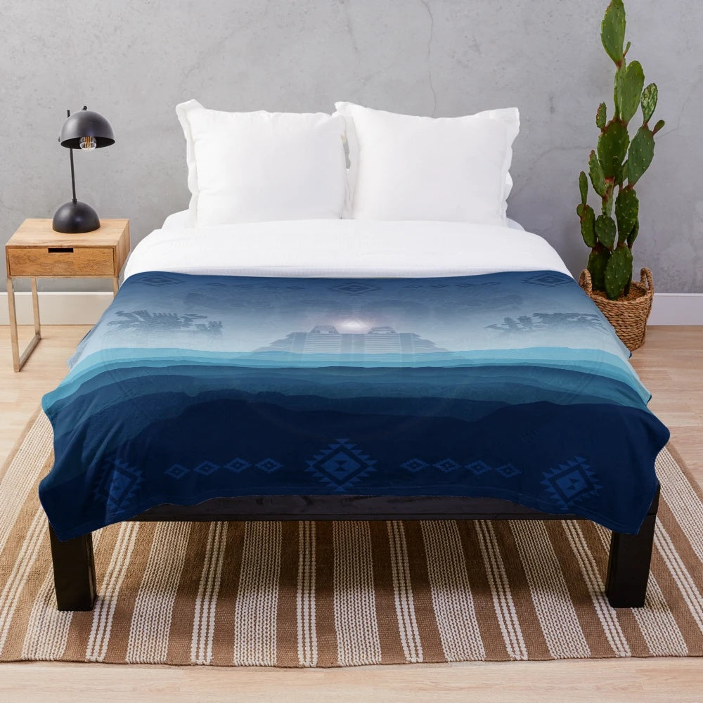 Aztec-inspired plush blanket with blue and orange patterns featuring the Aztec sun stone