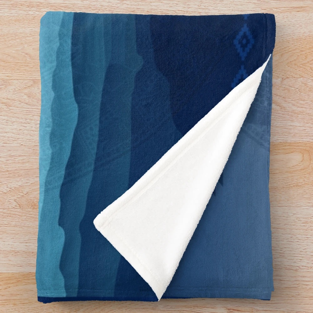 Aztec-inspired plush blanket with blue and orange patterns featuring the Aztec sun stone