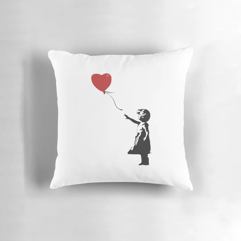 Banksy stencil artwork of a girl with a red heart-shaped balloon in windy weather, depicted on a pillow.