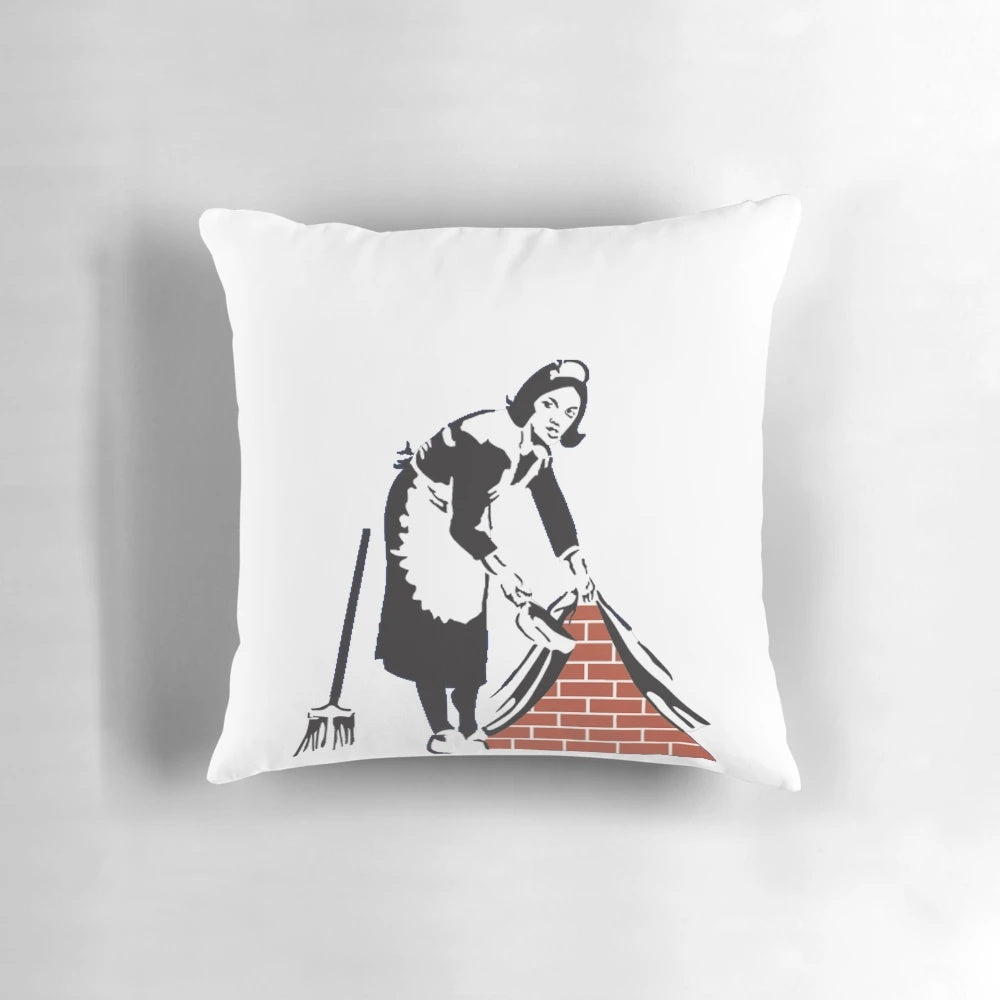 Banksy-inspired decorative pillow featuring the "Swept Under the Rug" artwork