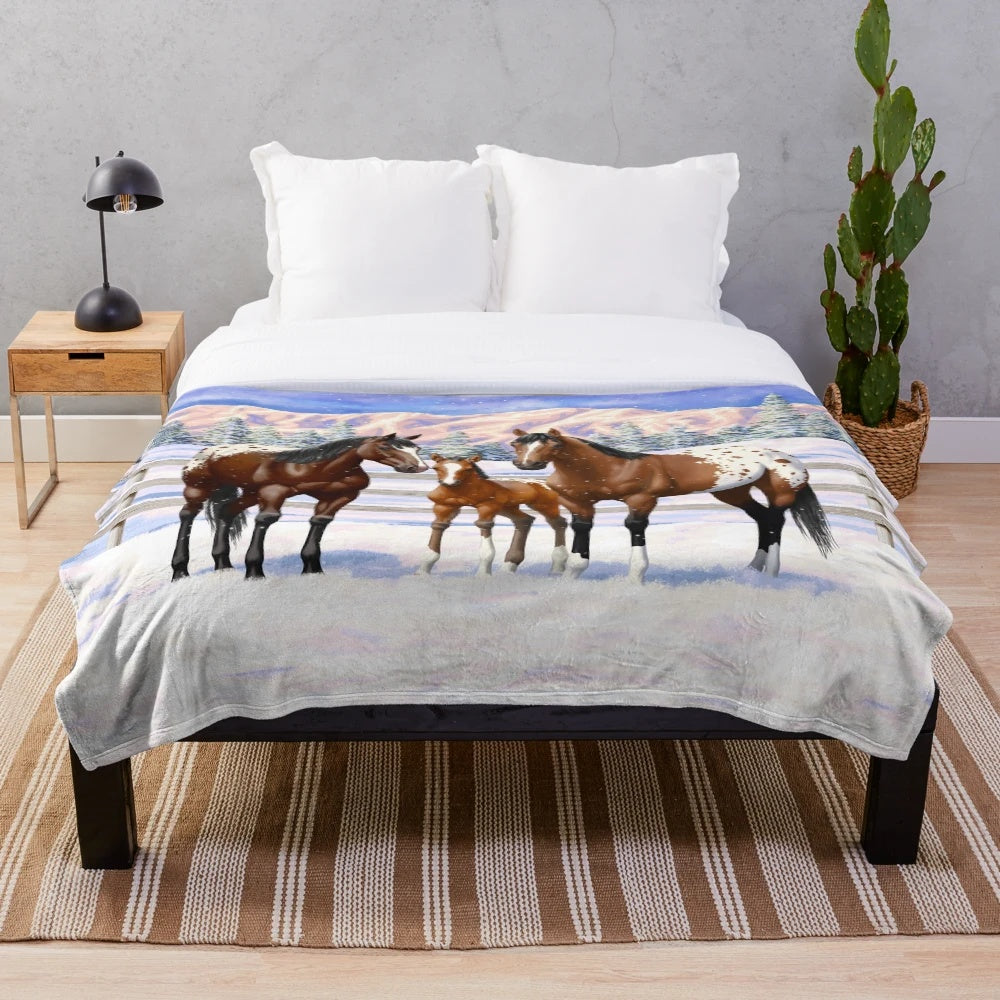 Appaloosa horses in a snowy winter scene on a plush blanket