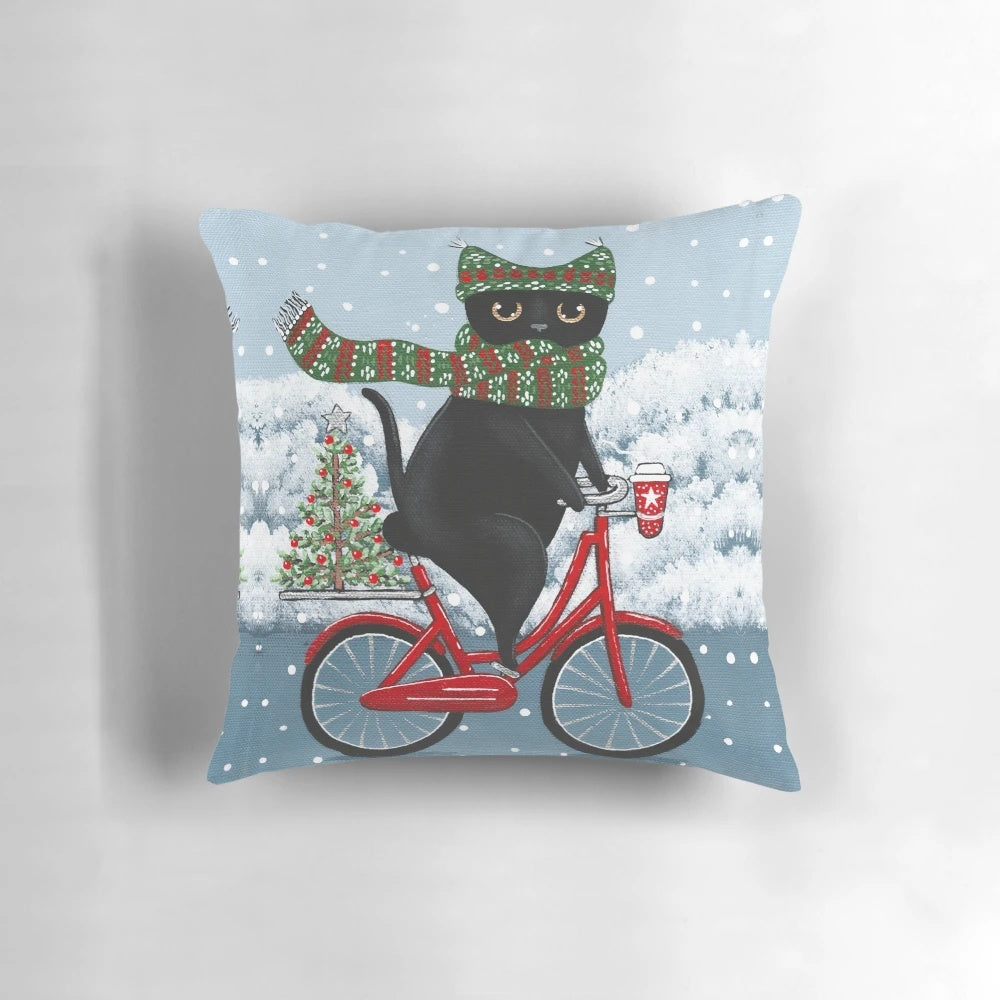 Black cat riding a bicycle with Christmas decorations on a pillow