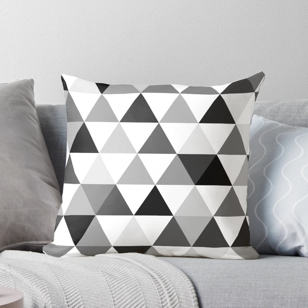 A decorative throw pillow featuring a modern, abstract design of triangles in black, grey, and white with a 3D, optical illusion effect.