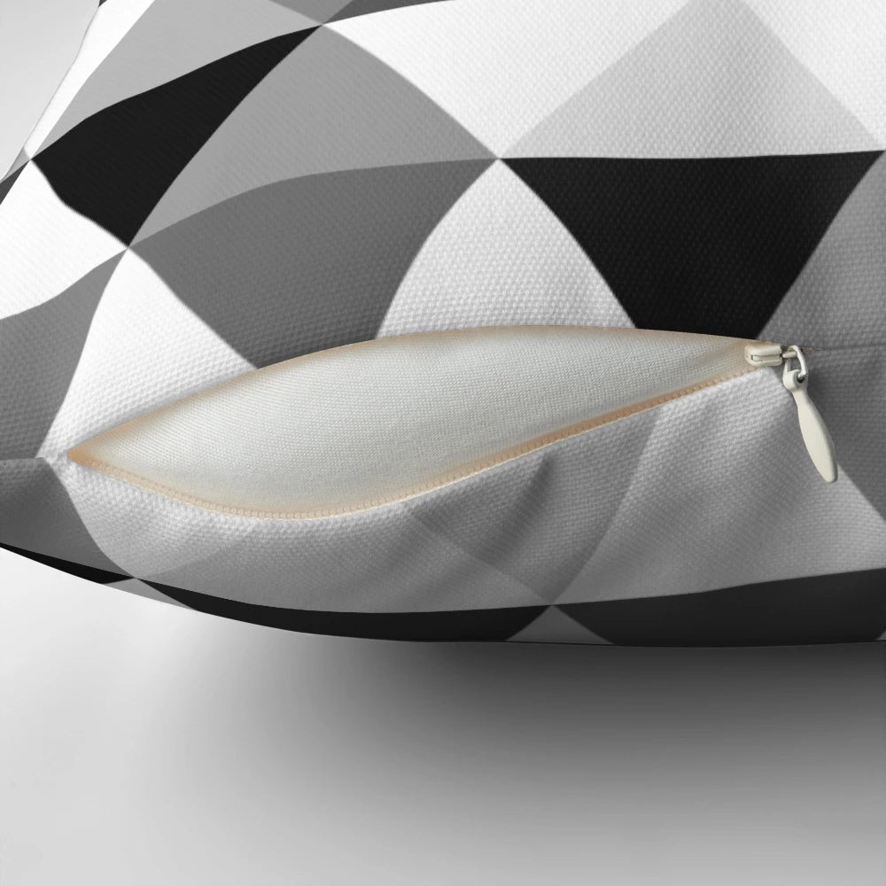 A decorative throw pillow featuring a modern, abstract design of triangles in black, grey, and white with a 3D, optical illusion effect.