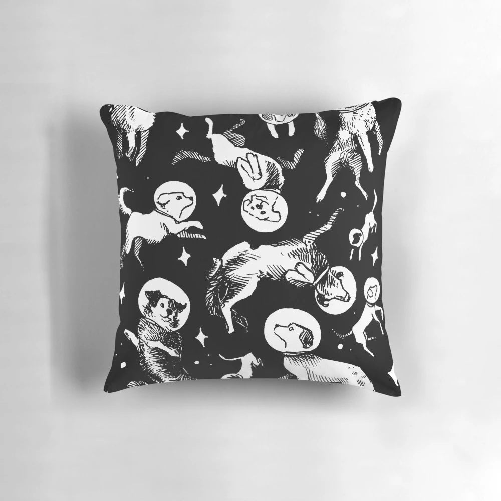 A plush pillow featuring a playful pattern of space-traveling dogs against a black background.