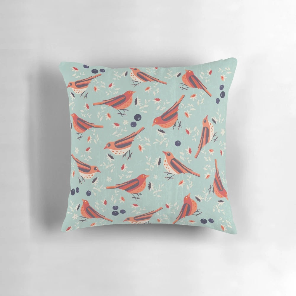 A colorful vintage-style pillow featuring a bluebird and floral pattern in shades of blue, orange, red, beige, and green.