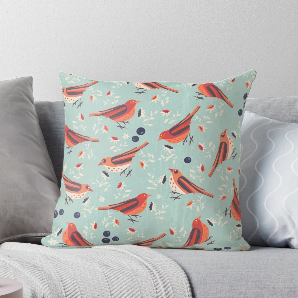 A colorful vintage-style pillow featuring a bluebird and floral pattern in shades of blue, orange, red, beige, and green.