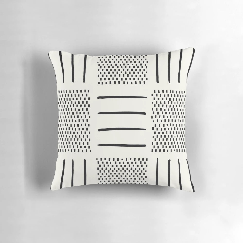 A cream and black patchwork pillow with a geometric, bohemian, and tribal design