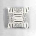 A cream and black patchwork pillow with a geometric, bohemian, and tribal design